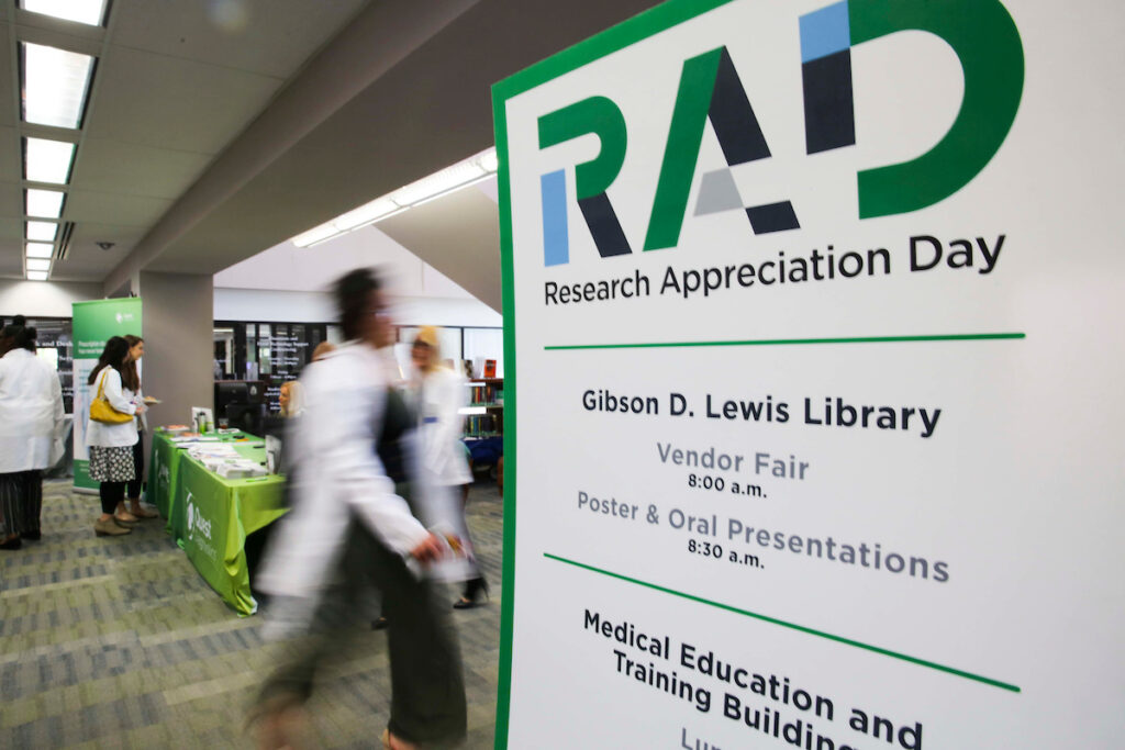 Research Appreciation Day poster and blurry figures walking around Gibson D. Lewis Library